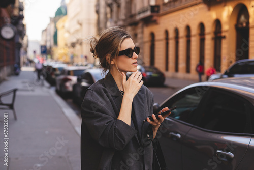 Attractive woman outdoors serious face thinking about question with hand on chin, thoughtful about confusing idea. Beautiful thoughtful young woman standing with hand on chin and looking away.