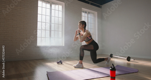 Slim young caucasian woman training in studio. Determined young female athlete exercising, doing a part of her cross fit training session - healthy lifestyle concept