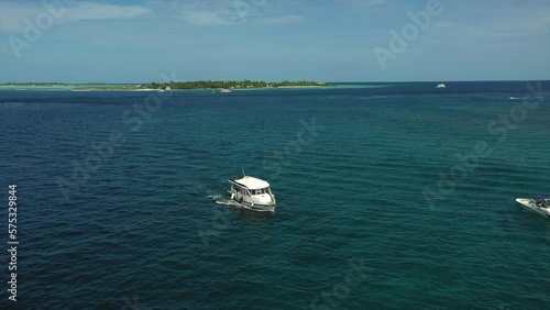 Aerial Panning Shot Of White Nautical Vessel Moving On Wavy Ocean Under Sky During Sunny Day - Thulusdhoo, Maldives photo