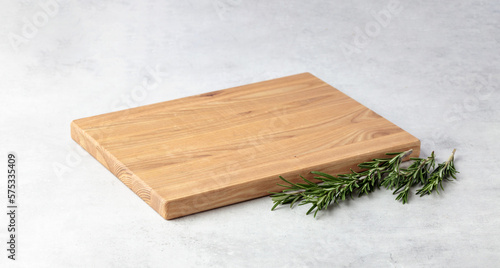 Fotografering Cutting board and rosemary on a grey stone table.