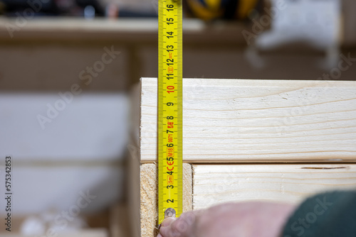 measuring the fixing points on a piece of lumber timber wood section with a bright yellow steel rule