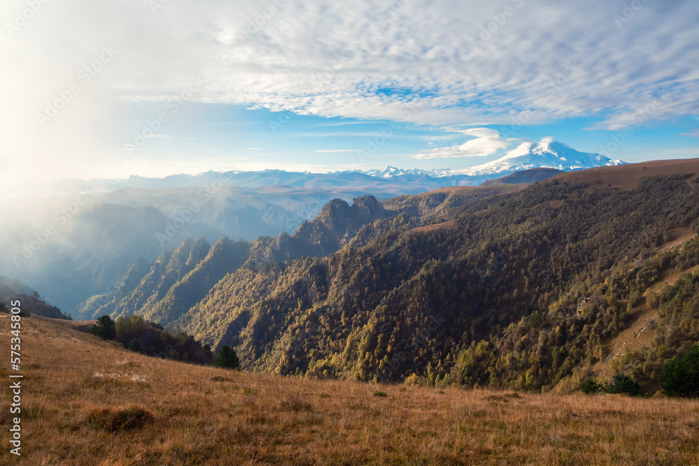 Obraz premium Mountains on a sunny foggy morning. Beautiful autumn mountain plateau, picturesque morning sunny view. View of the snowy Elbrus volcano in autumn. Russia, the Caucasus.