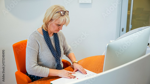 A 50-year-old woman works as a secretary at the front desk.