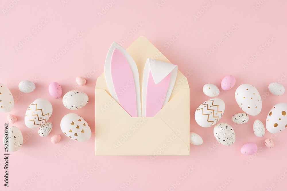 Easter decor concept. Flat lay photo of open envelope with easter bunny ears pink white eggs on isolated pastel pink background