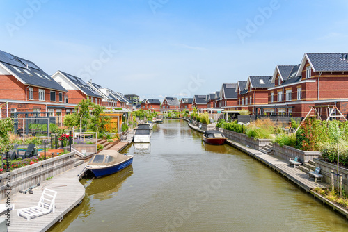 Modern energy efficient brick houses with rooftop solar panels along a canal in the Netherlands on a sunny summer day