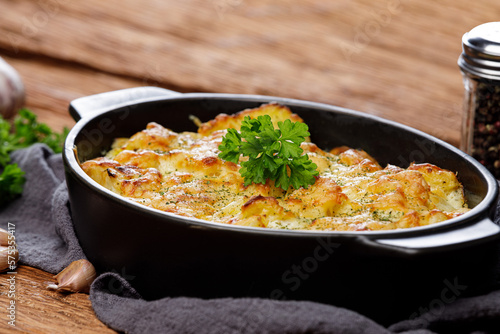 Potato casserole with cheese and parsley on wooden table. French cuisine, close up