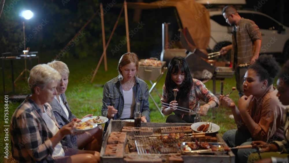 Group of friends having a meal and chatting happily at the campfire. Group of friends having a meal and chatting happily at the campfire.