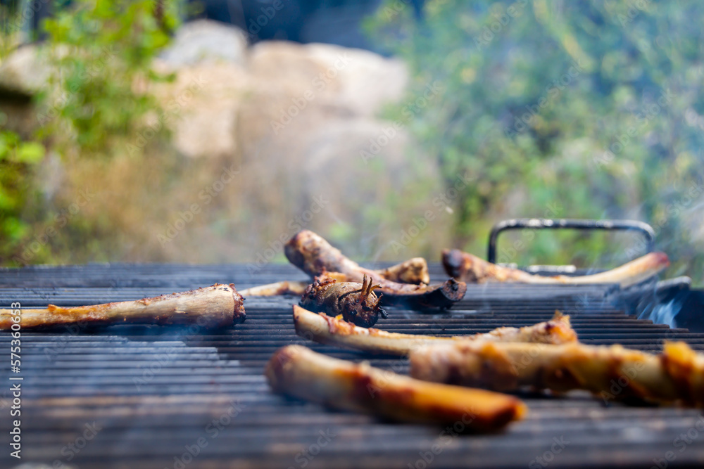 Bones from ribs on round open fire wood grill. Outdoors wood burning