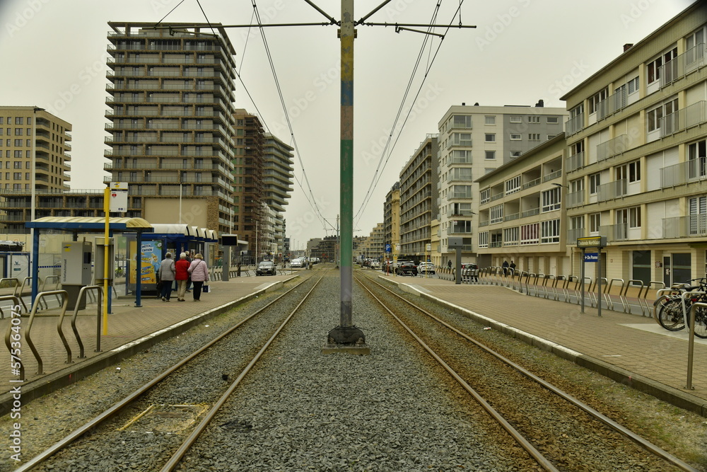 Fototapeta premium Ligne du Tram de la Côte avec ses caténaires reliant toutes les cités balnéaires belges sous un ciel sombre à Ostende 