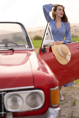 beautiful girl in retro style posing near vintage red cabriolet car. © Tsyb Oleh