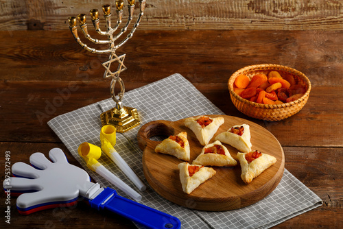 gometashi triangles cookies with mishloach manot jam for Purim laid out on a wooden board on a napkin next to the menorah rattle and whistle.