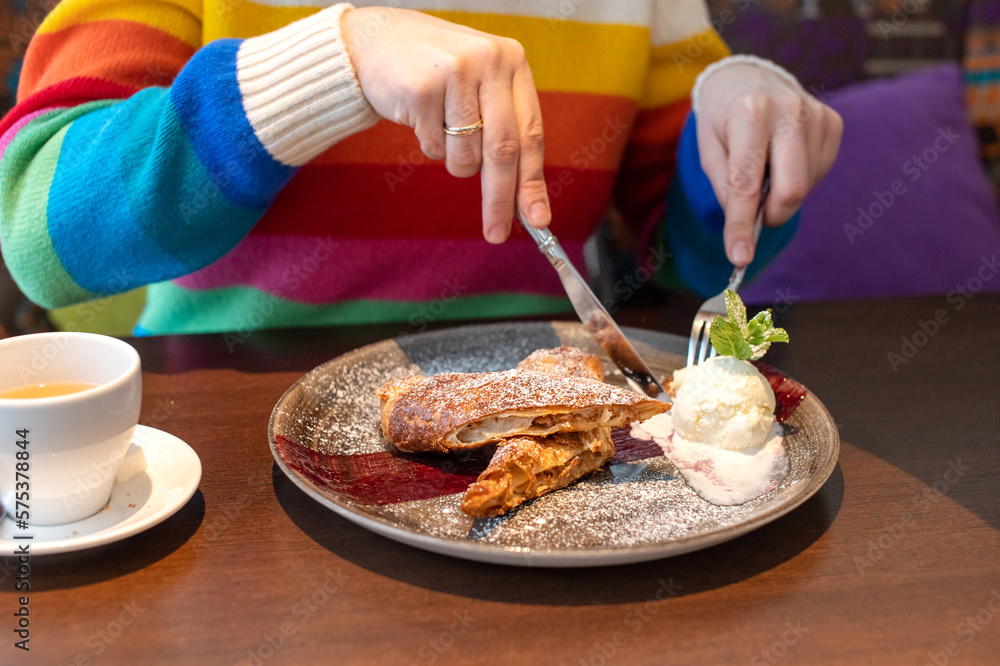 A woman in a bright sweater ordered a strudel with apples and ice cream