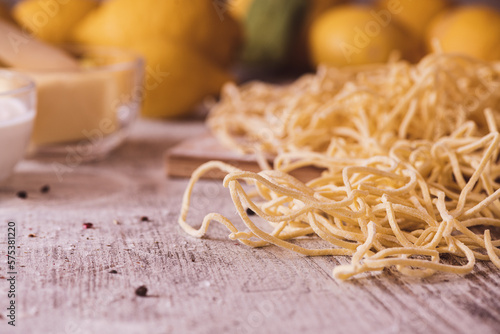 Fresh pasta  cream and butter on a wooden kitchen table with lemons in the background