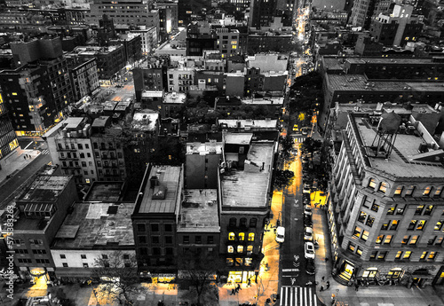 Yellow lights glowing in black and white cityscape overlooking the buildings of Manhattan in New York City at night
