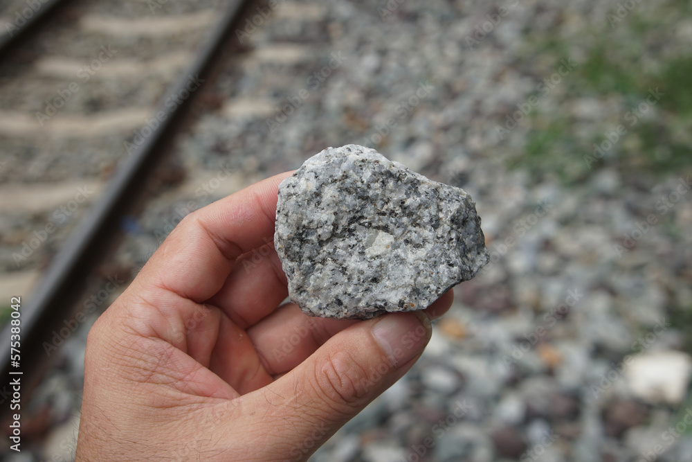 Raw specimen of granite igneous rock stone on Geologist's hand. The paving stones are used to attach the rail to the rail sleepers. Raw specimen of granite igneous rock stone on Geologist's hand. The paving stones are used to attach the rail to the rail sleepers.