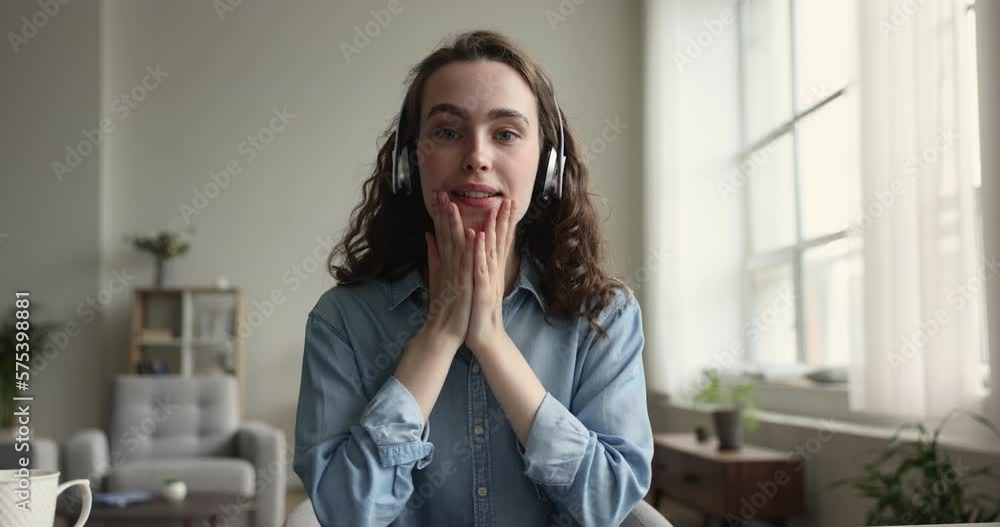 Smiling young 20s woman in headphones make video call, looking at camera enjoy talk, record webinar, participate in stream event with subscribers. Vlogging, communication using modern wireless tech Smiling young 20s woman in headphones make video call, looking at camera enjoy talk, record webinar, participate in stream event with subscribers. Vlogging, communication using modern wireless tech