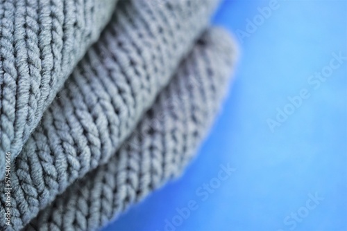 Cozy gray knitted sweater on blue table  copy space