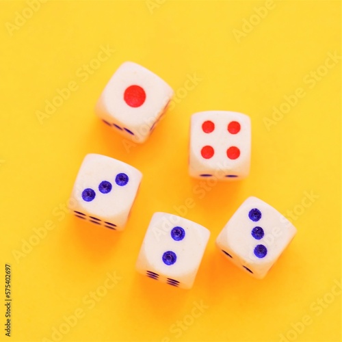 Five dice with different numbers on a orange sunny table