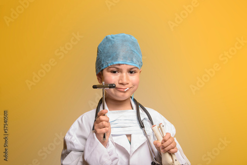 Adorable future doctor 7 years old boy isolated on yellow. photo
