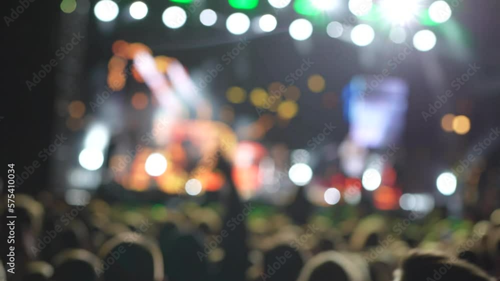 Illuminated and blurry dancing crowd at a concert. Silhouette of people at a party during the concert. People wave their hands, greeting their musician, singer. Illuminated and blurry dancing crowd at a concert. Silhouette of people at a party during the concert. People wave their hands, greeting their musician, singer.
