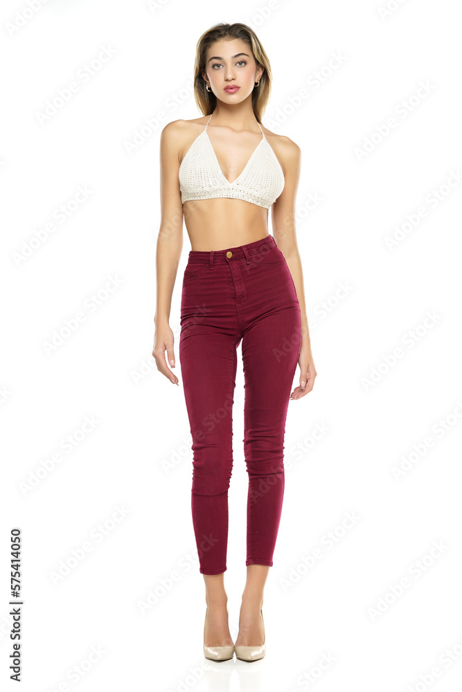 a young woman in burgundy jeans and top, and high heels shoes posing on a white background a young woman in burgundy jeans and top, and high heels shoes posing on a white background