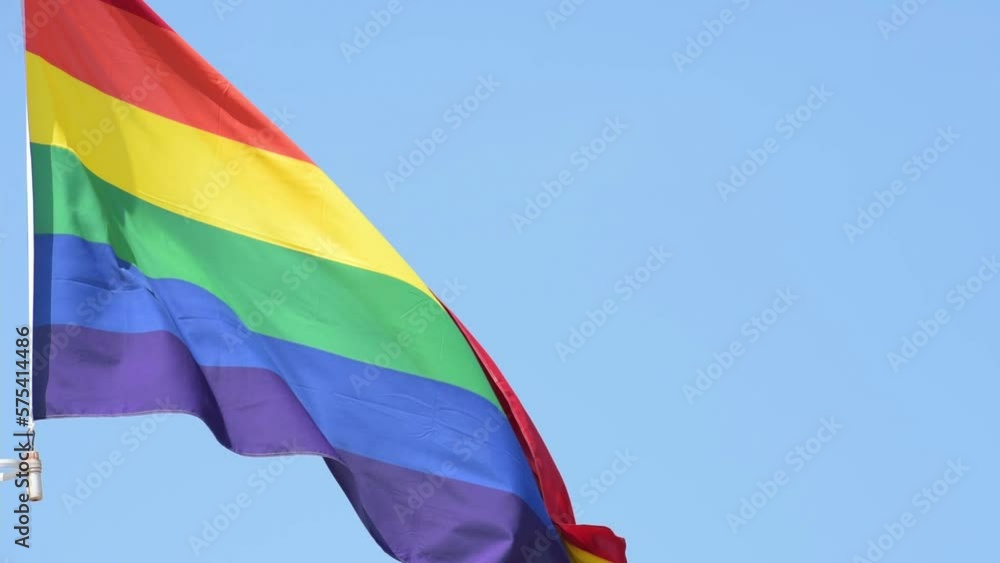 Rainbow flag waving in the wind on a sunny day.
Rainbow flag waving in the wind on a sunny day.
