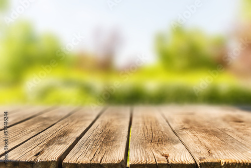 Wooden table on the background of blurry trees in the park in the summer season. Sunny weather.