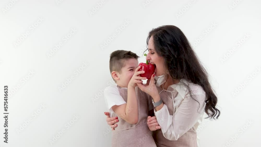 mother biting red bell pepper boy grimacing hugging space for text fun spending time together joke grocery store delicious vegetables vegetarian food wearing apron in kitchen mother and son mother biting red bell pepper boy grimacing hugging space for text fun spending time together joke grocery store delicious vegetables vegetarian food wearing apron in kitchen mother and son