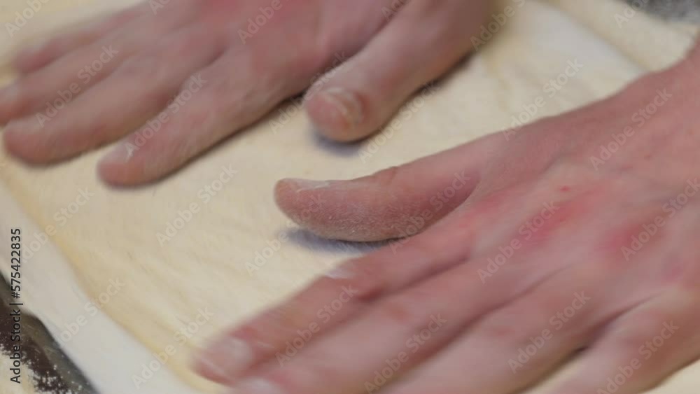 A close-up of the cook rotates the dough in a circle with his hands and forms a pizza. The pizzeria chef kneads the dough for traditional Italian pizza. A close-up of the cook rotates the dough in a circle with his hands and forms a pizza. The pizzeria chef kneads the dough for traditional Italian pizza.