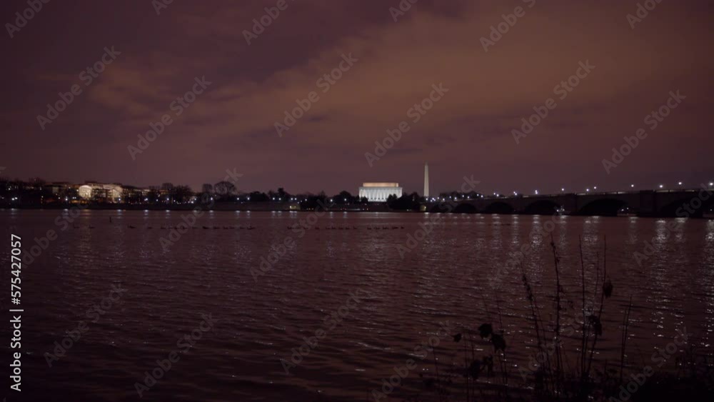 Lockdown Shot Of Illuminated Famous Monuments By Rippled River Against Sky During Night - Washington, District of Columbia Lockdown Shot Of Illuminated Famous Monuments By Rippled River Against Sky During Night - Washington, District of Columbia
