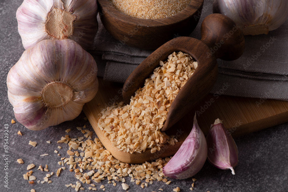 Dry garlic granules. Spice garlic. Dry garlic powder in a wooden bowl and spoon. Dry garlic granules. Spice garlic. Dry garlic powder in a wooden bowl and spoon.