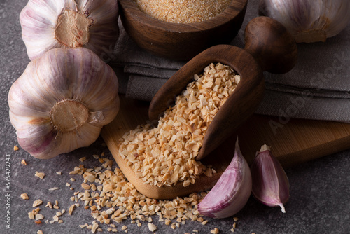 Dry garlic granules. Spice garlic. Dry garlic powder in a wooden bowl and spoon.