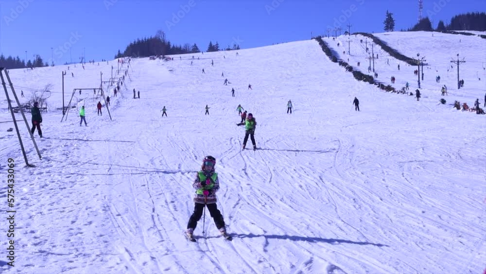 Front view action shot over beautiful mountains. Kids skiing in winter sport outfit with helmet and mask ride downhill. Front view action shot over beautiful mountains. Kids skiing in winter sport outfit with helmet and mask ride downhill.