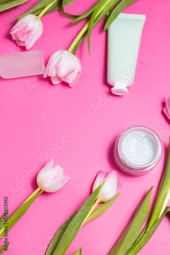 Beauty background with natural cosmetic, flowers. Flat lay image on pink