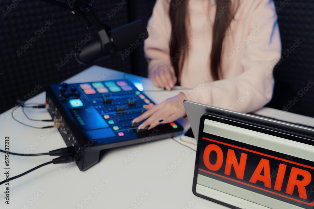From above anonymous female adjusting fader on mixing console while sitting at table and recording podcast in studio From above anonymous female adjusting fader on mixing console while sitting at table and recording podcast in studio