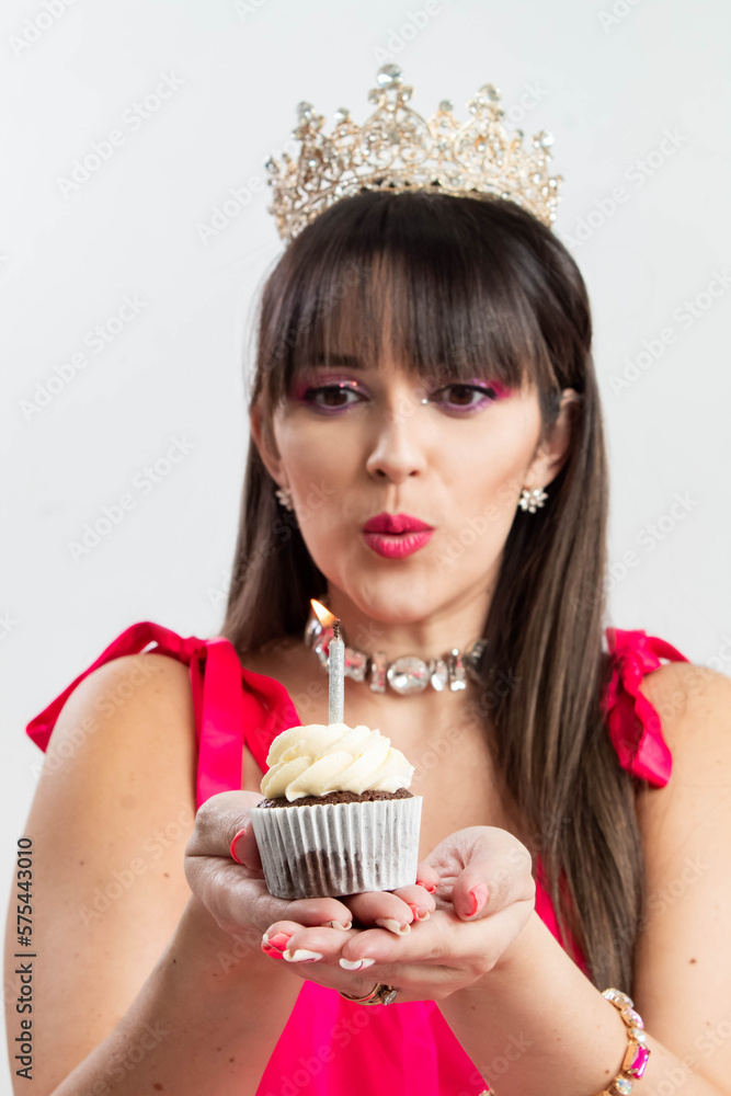Vertical photo of cute latina girl celebrating her birthday with cupcake, candles, cup, wearing beautiful and elegant fuccia dress