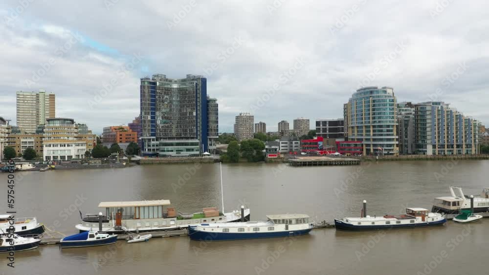 boats moored at long wooden pier in Thames river. Modern apartment buildings on other side boats moored at long wooden pier in Thames river. Modern apartment buildings on other side