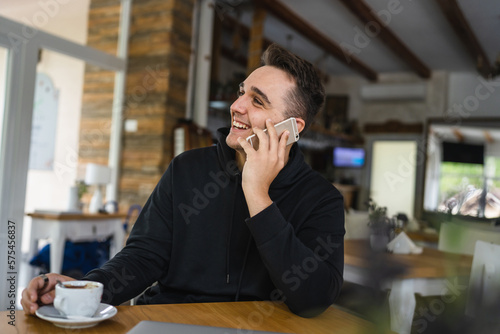 one man use mobile phone while sit at the table at restaurant