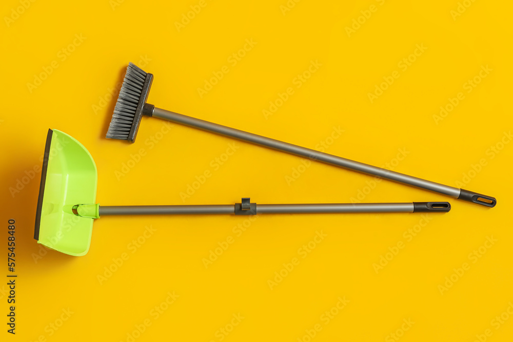 Cleaning broom with dustpan on yellow background Cleaning broom with dustpan on yellow background
