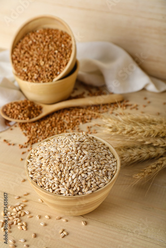 Bowl with pearl barley on wooden background
