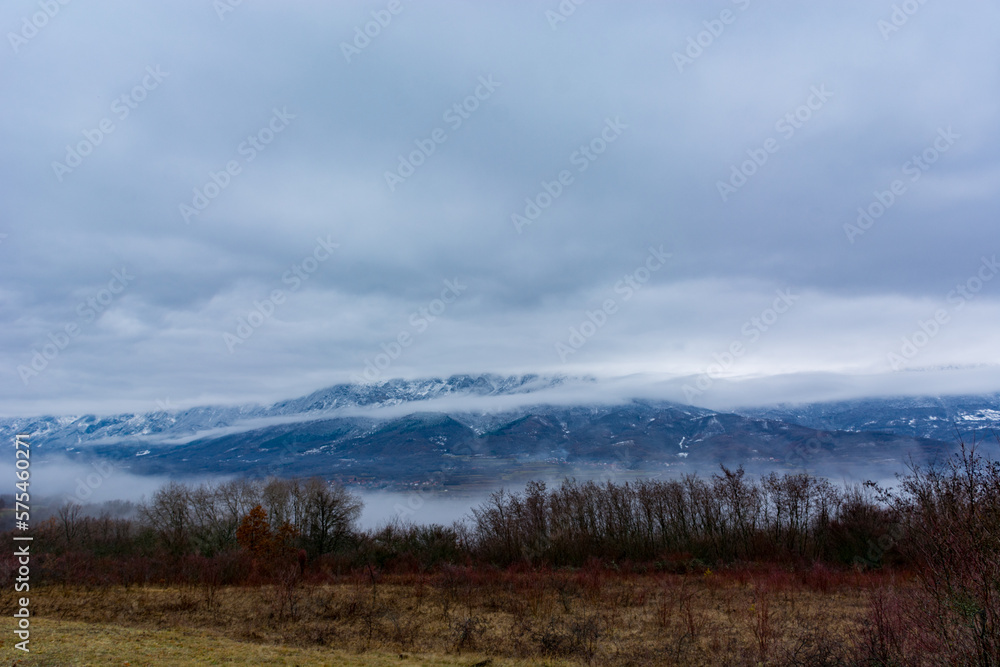 A captivating winter landscape featuring a dry mountain range with snow and clouds adds to the scenes grandeur. The overcast weather contributes to the image serene atmosphere