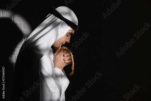 Praying Muslim man in dark room photo