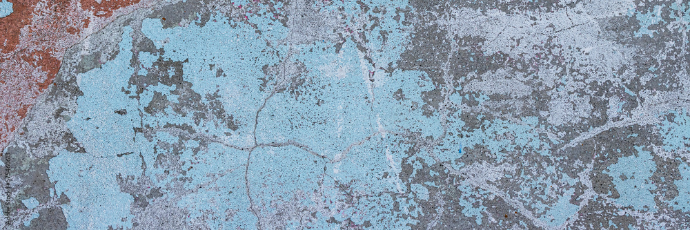 Fototapeta premium Vintage wall texture. Rough surface of the plastered concrete wall of the building. A pattern with many cracks and old faded peeling paint. Wide panoramic texture for background and design.