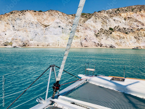 A spectacular sea view at the bow of a sailing catamaran anchored at a bay of Milos island during Greek Summer