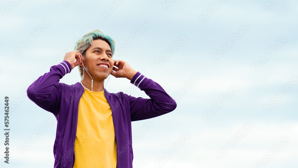hombre joven moreno sonriente con audífonos ropa morada y amarilla con pelo pintado feliz 