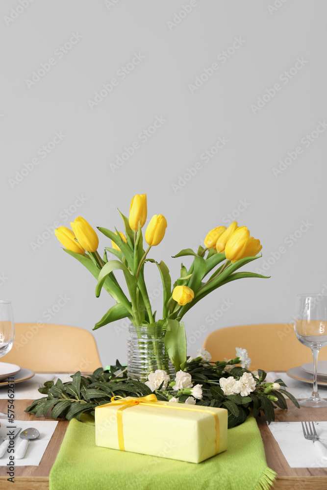Table setting for International Women's Day celebration with gifts and tulip flowers on white background