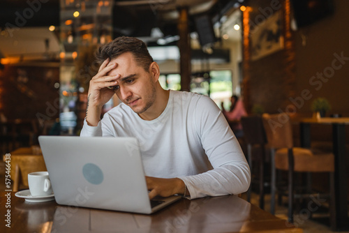 one man work on laptop computer at cafe with bad news worried