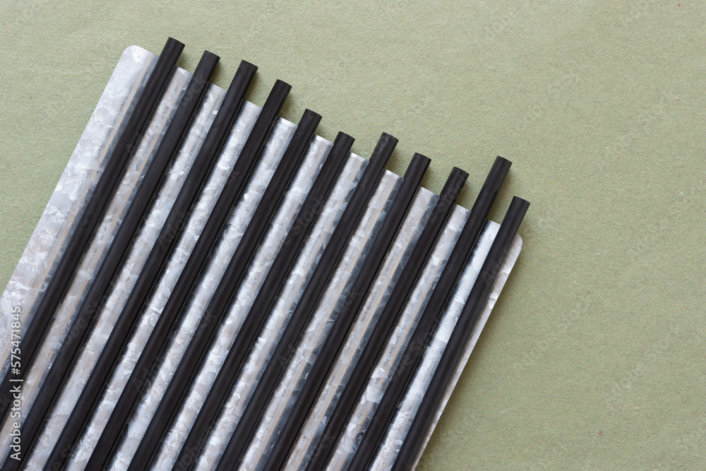 synthetic black straws or thin, hollow tube made of black plastic on galvanized and corrugated metal plate on paper