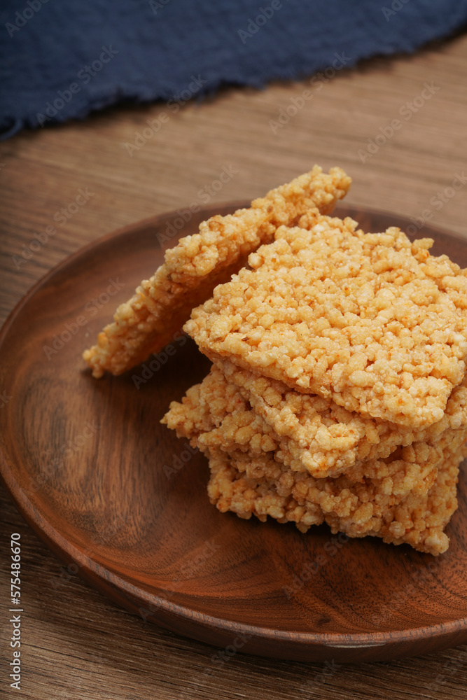 A plate of crispy rice is on the wooden table A plate of crispy rice is on the wooden table
