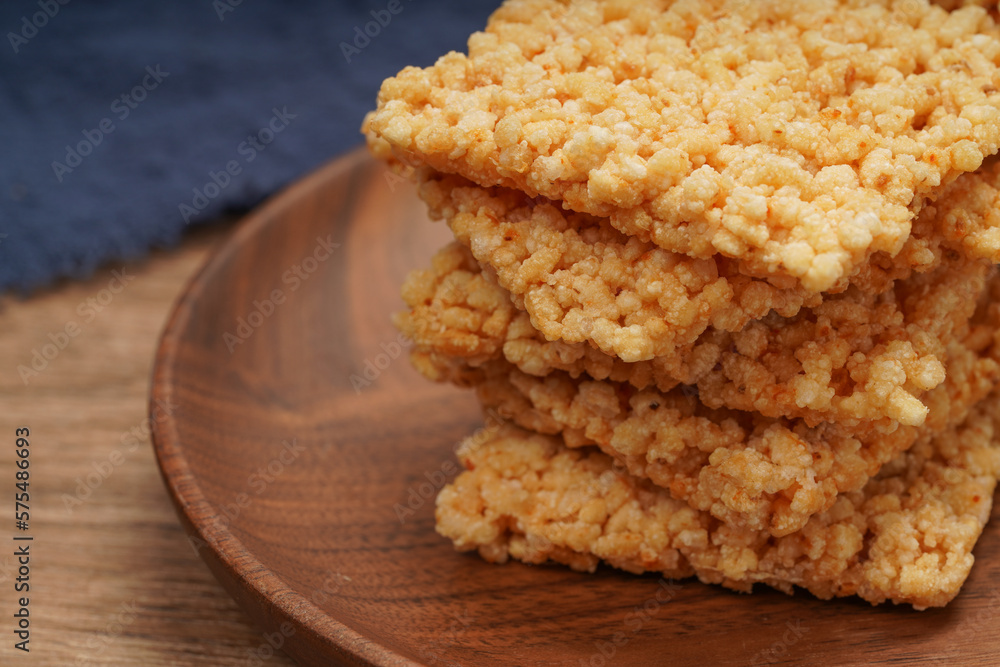 A plate of crispy rice is on the wooden table A plate of crispy rice is on the wooden table